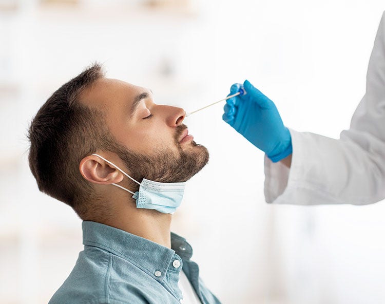 Man getting a nasal swab COVID-19 test by a medical professional in blue gloves.